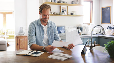 Buy stock photo Cropped shot of a handsome young man looking cheerful while going through his budget at home