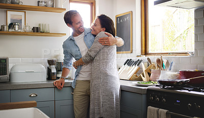 Buy stock photo Cropped shot of an affectionate young couple embracing each other while standing in their kitchen at home