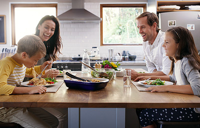 Buy stock photo Cropped shot of two affectionate young parents enjoying a meal with their kids at home