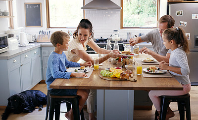 Buy stock photo Cropped shot of two affectionate young parents having breakfast with their two kids in their kitchen at home