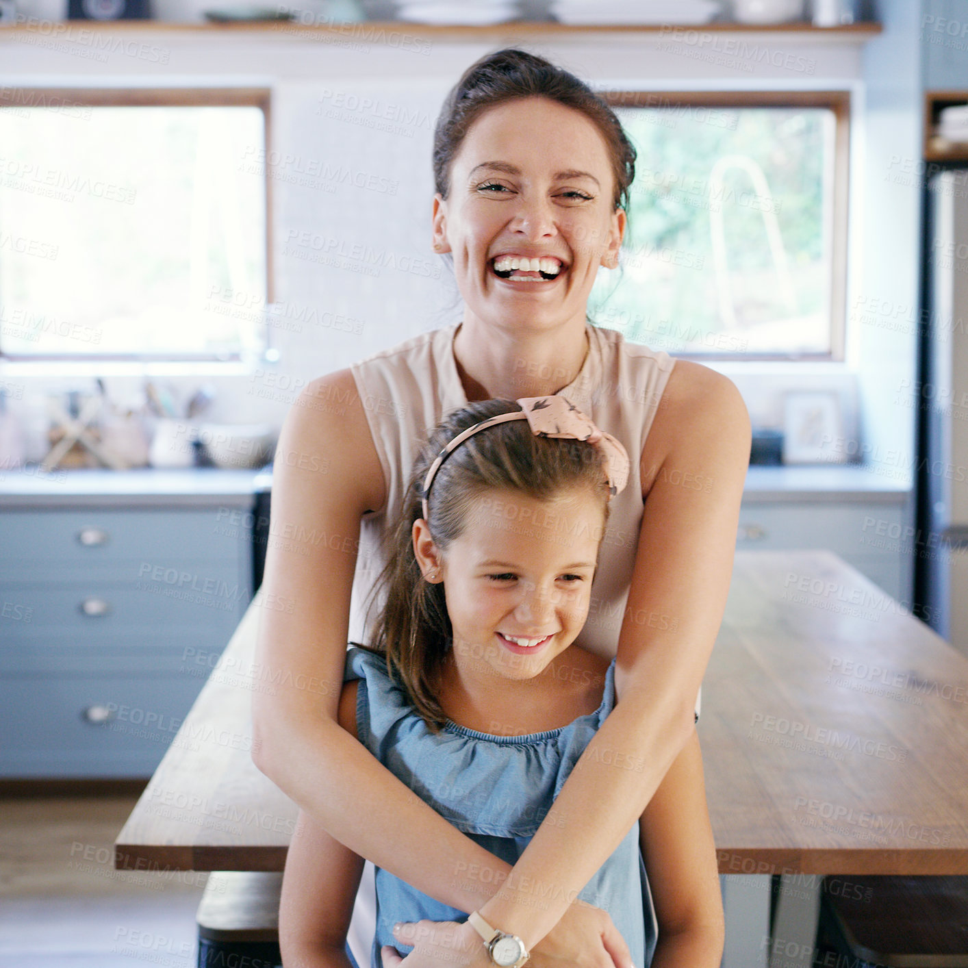 Buy stock photo Cropped shot of an affectionate young mother looking cheerful while holding her daughter in their kitchen at home