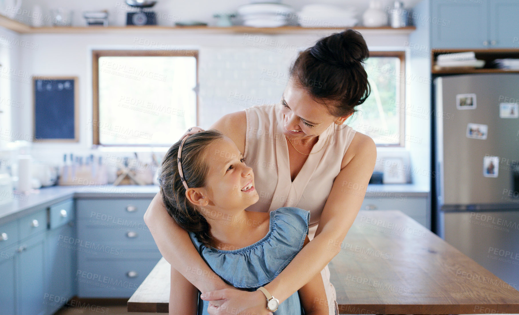Buy stock photo Cropped shot of an affectionate young mother smiling at her daughter while standing in their kitchen at home