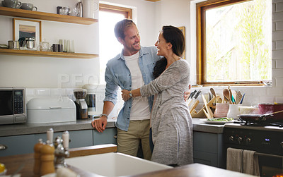 Buy stock photo Cropped shot of an affectionate young couple embracing each other while standing in their kitchen at home