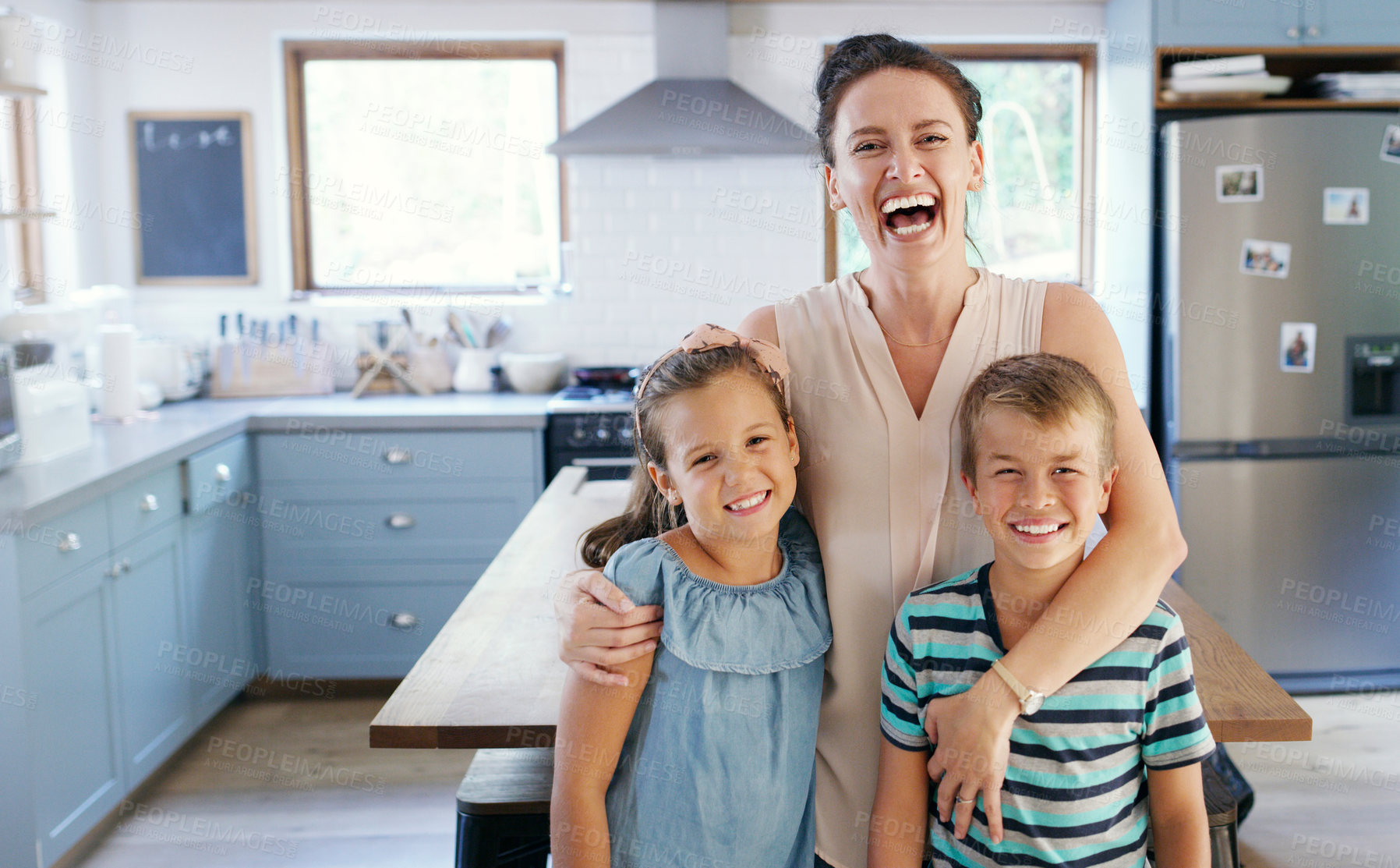 Buy stock photo Cropped portrait of an affectionate young mother looking ecstatic while holding her two kids in their kitchen at home