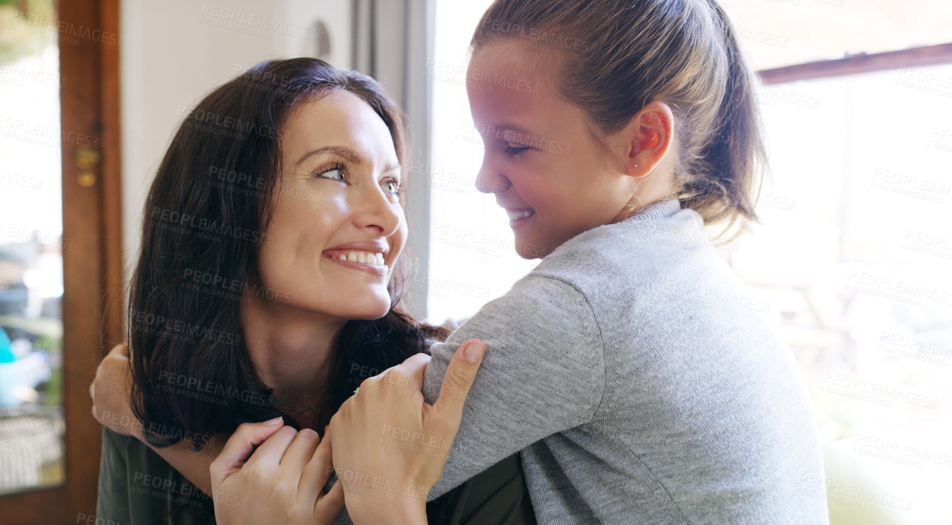 Buy stock photo Cropped shot of an affectionate young mother smiling at her daughter while spending time with her at home