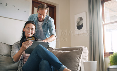 Buy stock photo Cropped shot of an affectionate young couple using a digital tablet and a credit card to shop online at home