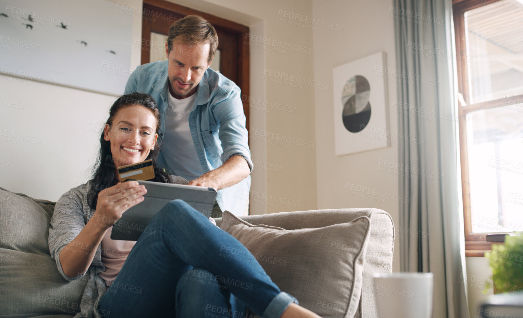 Buy stock photo Cropped shot of an affectionate young couple using a digital tablet and a credit card to shop online at home