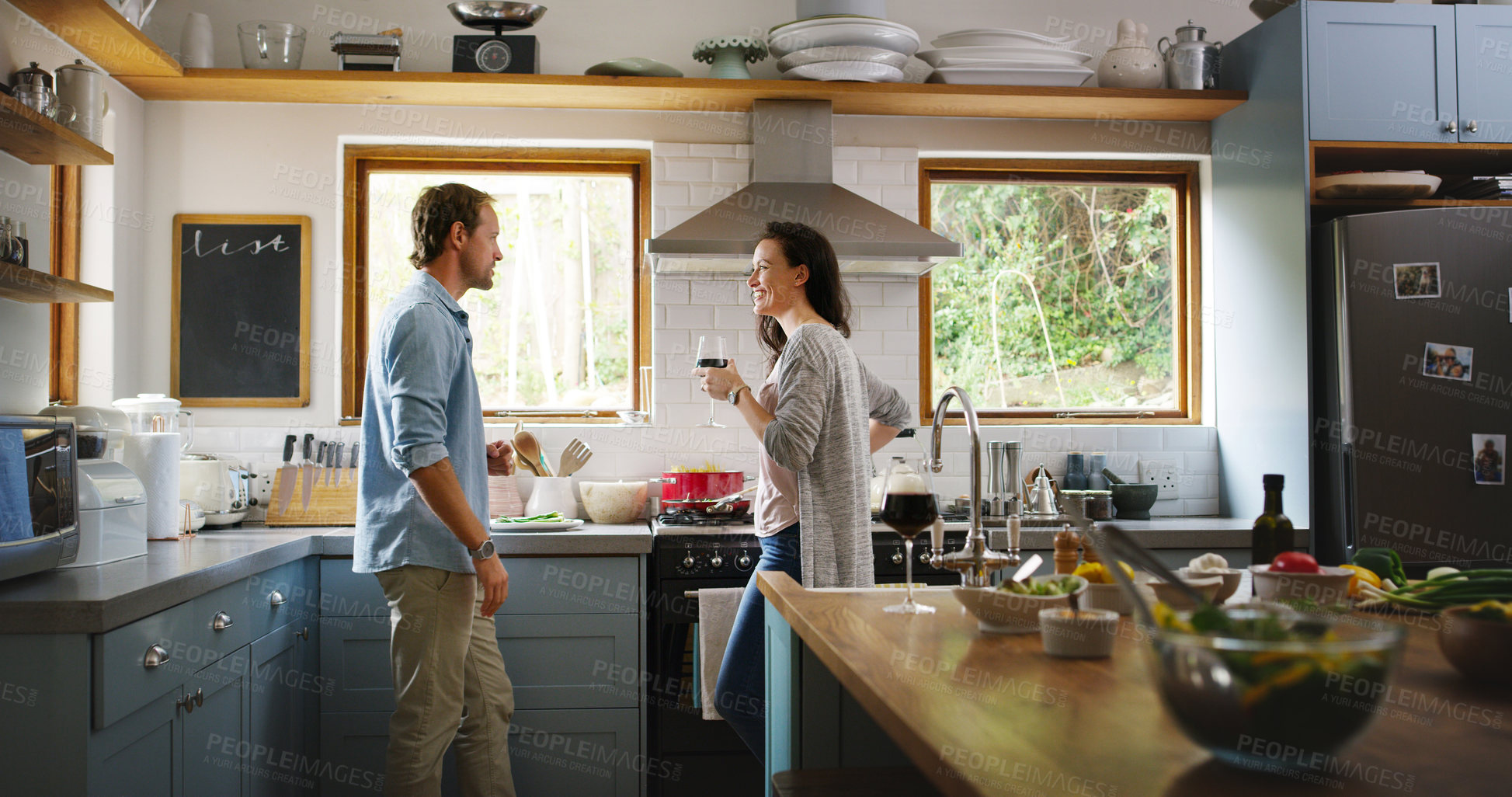 Buy stock photo Cropped shot of an affectionate young couple having a discussion while cooking in their kitchen at home