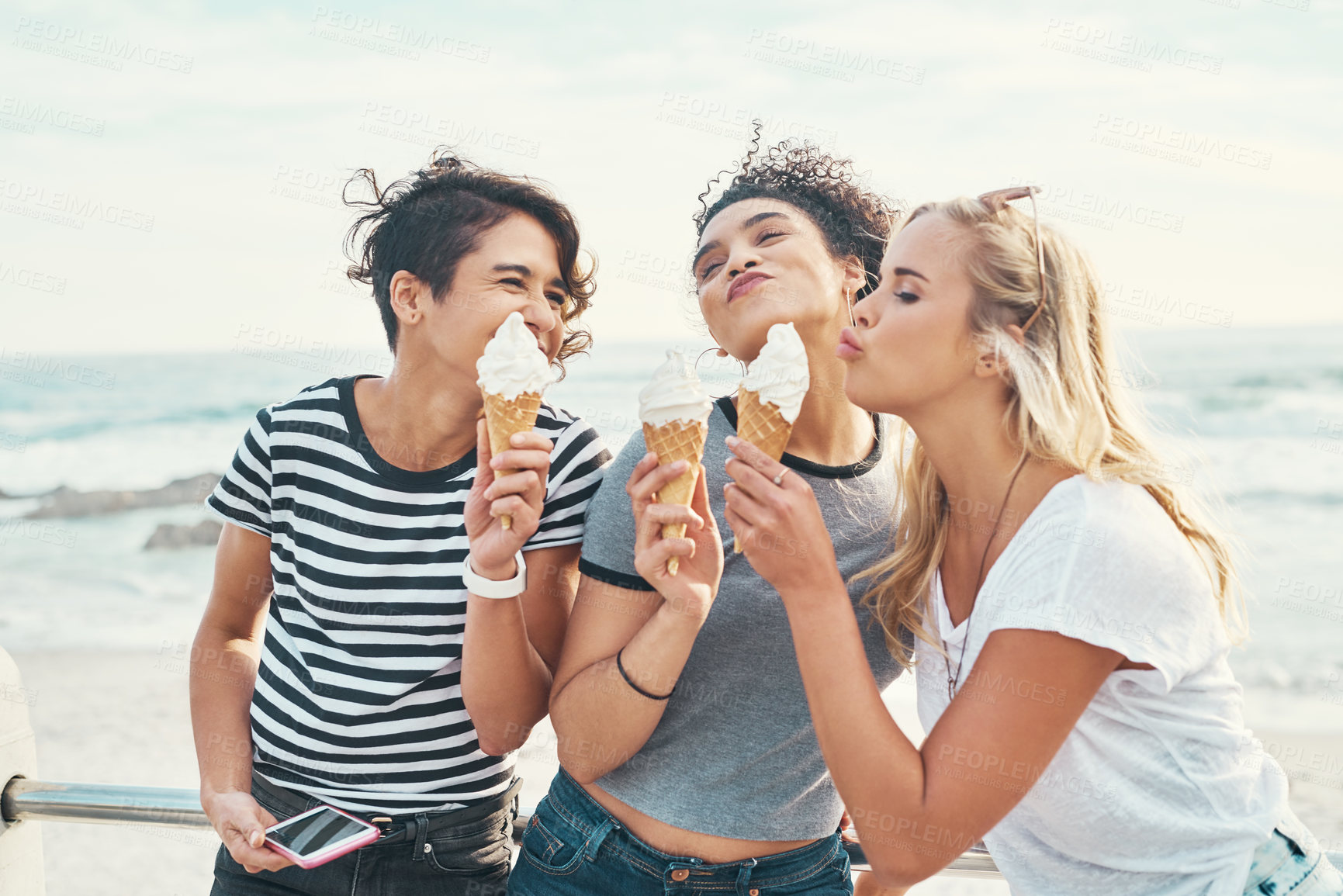 Buy stock photo Cropped shot of three friends eating ice while out on the promenade