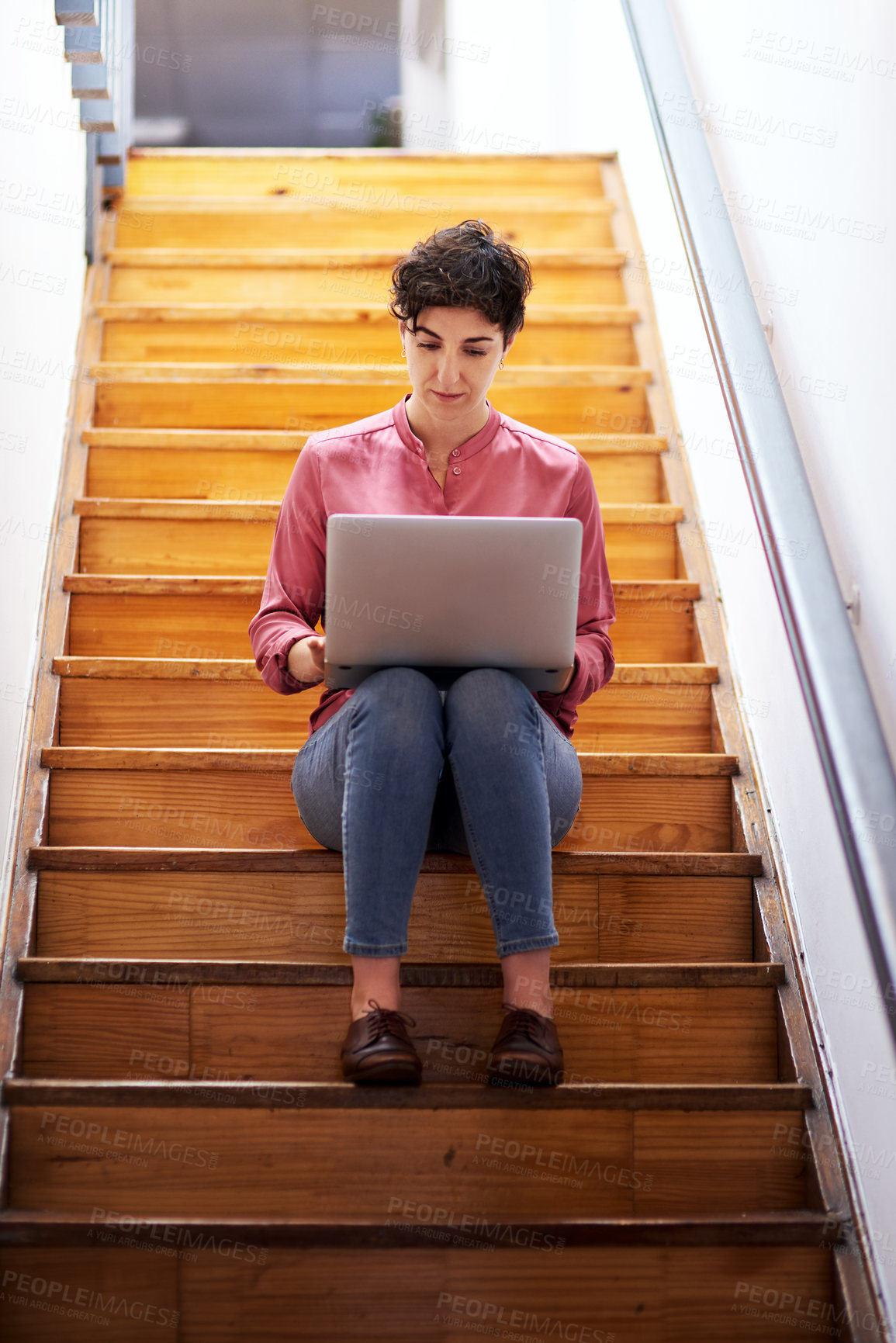 Buy stock photo Full length shot of an attractive young businesswoman sitting alone on a staircase and using her laptop in the office