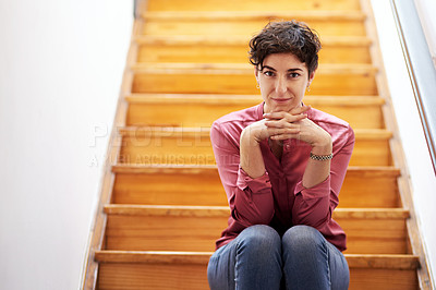 Buy stock photo Cropped portrait of an attractive young businesswoman sitting alone on a wooden staircase in her office