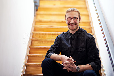 Buy stock photo Cropped portrait of a handsome young businessman sitting alone on the wooden staircase in his office