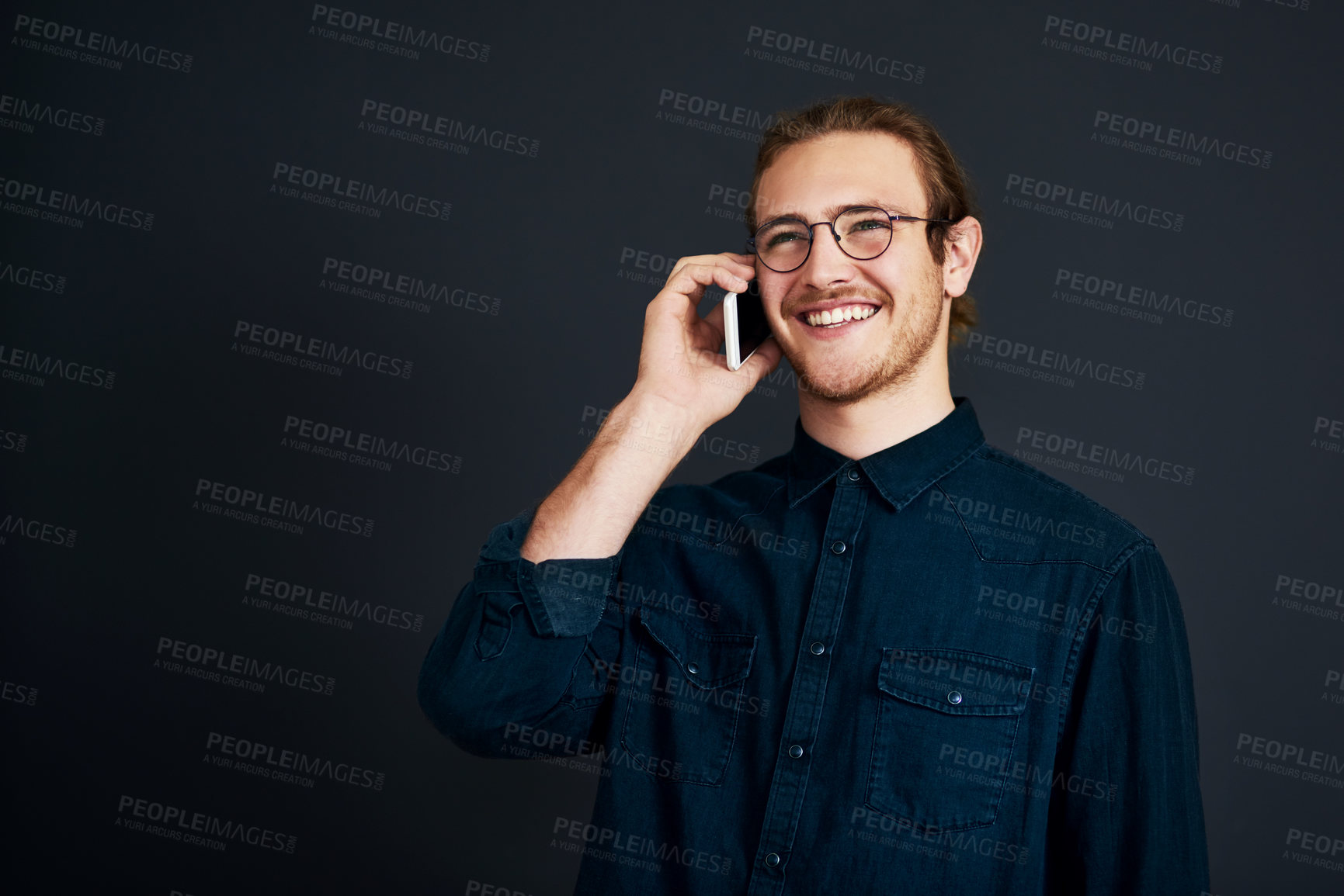 Buy stock photo Cropped shot of a handsome young businessman standing and talking on his cellphone against a black background in the studio