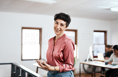 Buy stock photo Cropped portrait of an attractive young businesswoman holding a tablet while her colleagues work behind her in the office