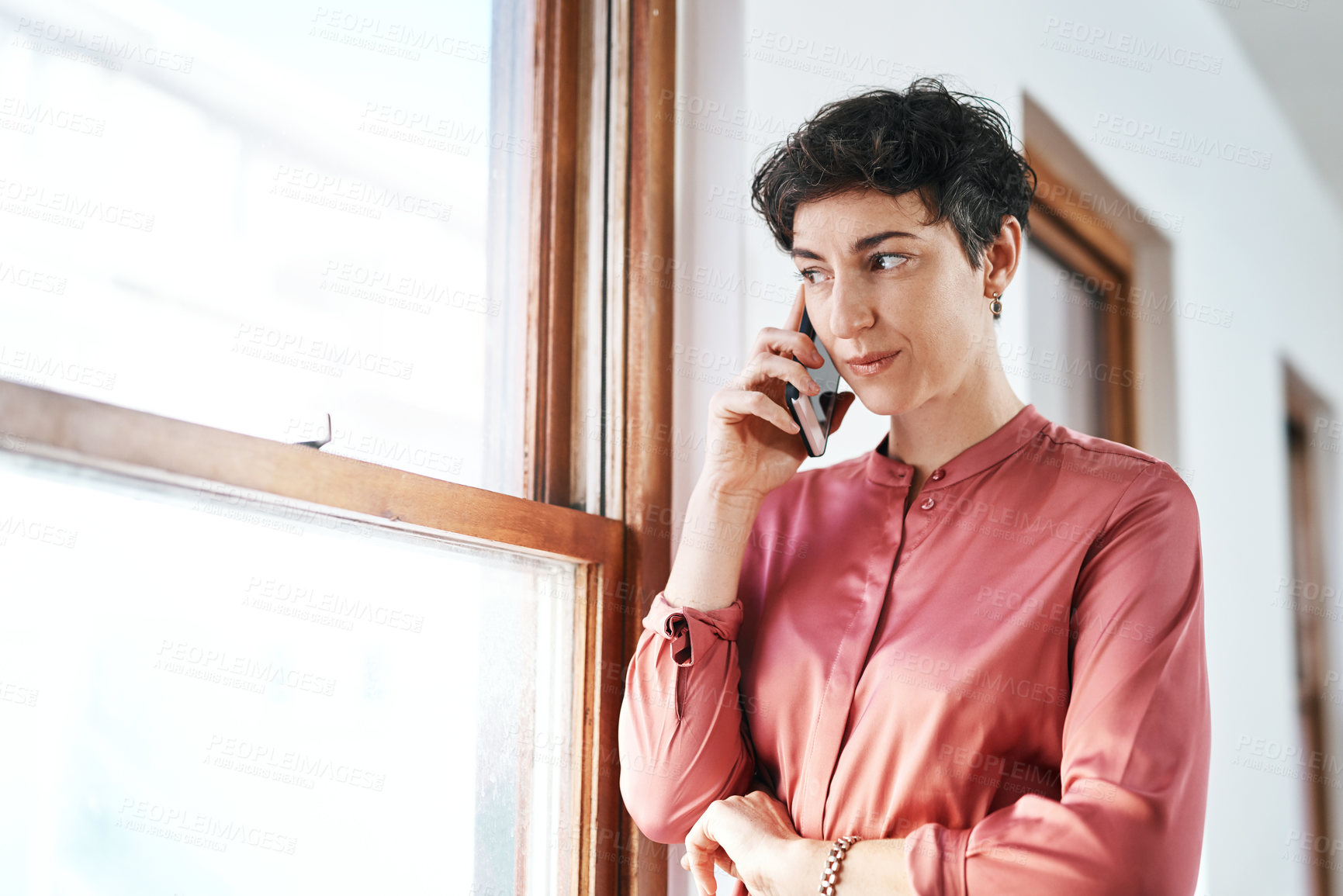 Buy stock photo Cropped shot of an attractive young businesswoman standing alone in the office and talking on her cellphone