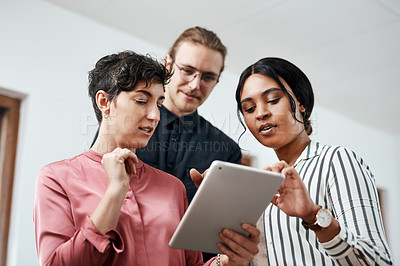 Buy stock photo Cropped shot of a diverse group of businesspeople standing together and using a tablet in the office