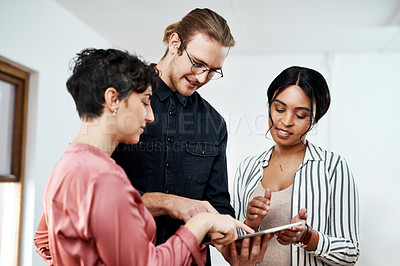 Buy stock photo Cropped shot of a diverse group of businesspeople standing together and using a tablet in the office