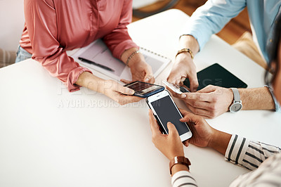 Buy stock photo Cropped shot of an unrecognizable group of businesspeople sitting together and using their cellphones during a meeting
