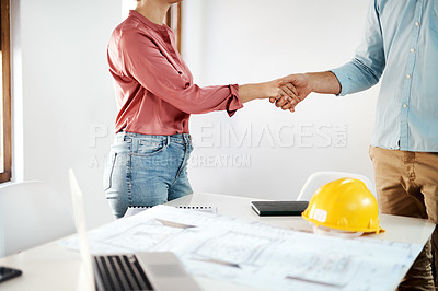 Buy stock photo Cropped shot of two unrecognizable businesspeople shaking hands in agreement over building plans in the office