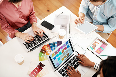 Buy stock photo High angle shot of an unrecognizable group of businesspeople sitting together and using technology during a meeting in the office