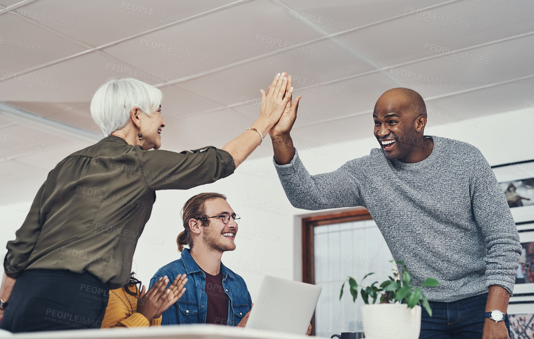 Buy stock photo Cropped shot of two cheerful businesspeople giving each other a high five inside of the office during the day
