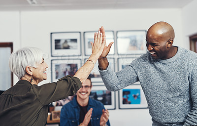 Buy stock photo Cropped shot of two cheerful businesspeople giving each other a high five inside of the office during the day