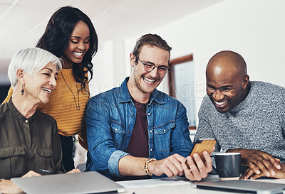 Buy stock photo Cropped shot of a group of cheerful businesspeople browsing on a cellphone together inside of the office during the day