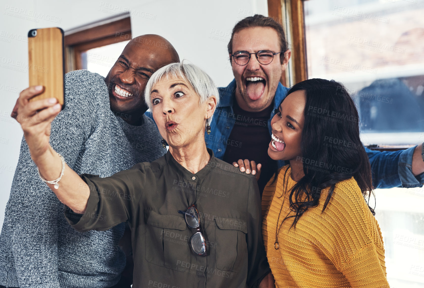 Buy stock photo Cropped shot of a group of cheerful businesspeople taking a self portrait together with a cellphone inside of the office
