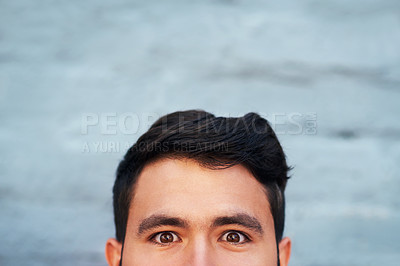 Buy stock photo Cropped portrait of a young man's face peeking from below against a brick wall