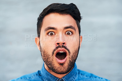Buy stock photo Cropped portrait of a handsome young man looking shocked while standing against a brick wall