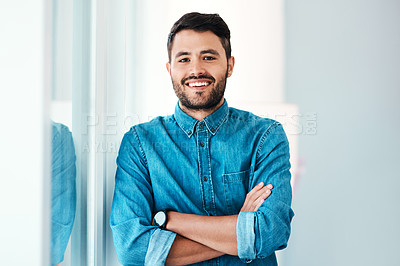 Buy stock photo Cropped portrait of a handsome young businessman smiling while standing with his arms crossed in an office
