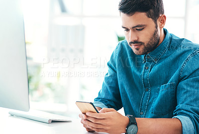 Buy stock photo Cropped shot of a handsome young businessman using a mobile phone while sitting in an office