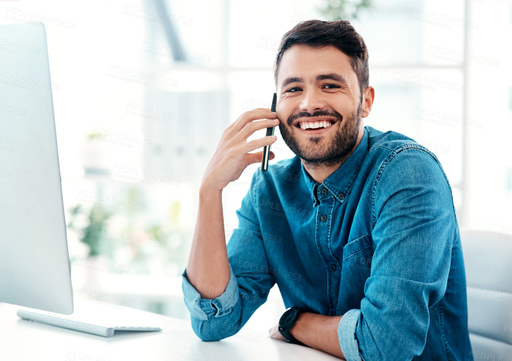 Buy stock photo Cropped shot of a handsome young businessman smiling while taking a phonecall in an office