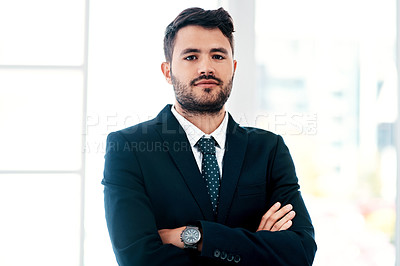Buy stock photo Cropped portrait of a handsome young businessman standing with his arms crossed in a modern office