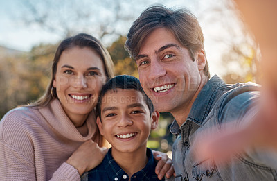 Buy stock photo Shot of a happy young family taking a selfie together in the park