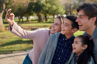Buy stock photo Shot of a happy young family taking a selfie together in the park