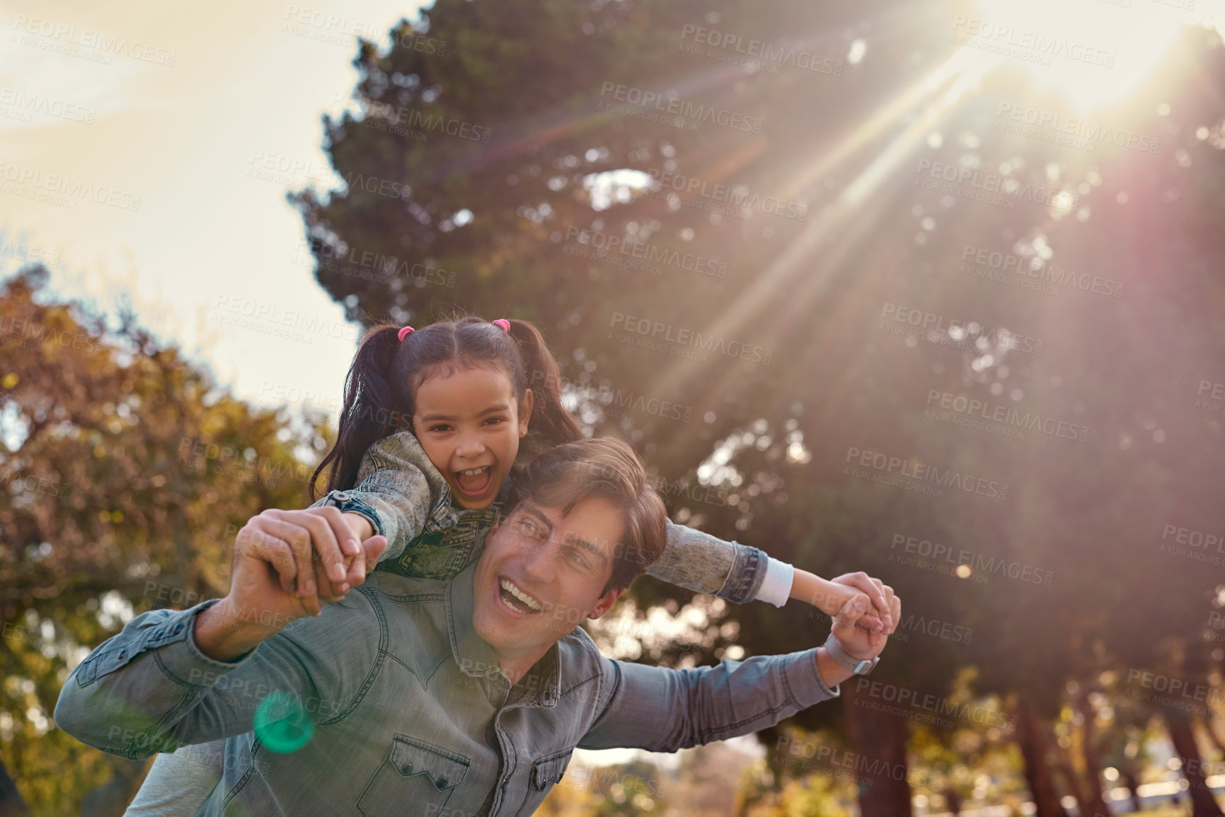 Buy stock photo Shot of an adorable little girl enjoying a piggyback ride with her father at the park