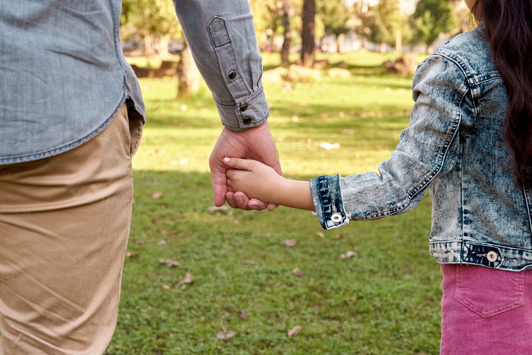 Buy stock photo Cropped shot of a little girl holding her father's hand while going for a walk in the park