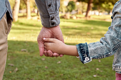 Buy stock photo Cropped shot of a little girl holding her father's hand while going for a walk in the park