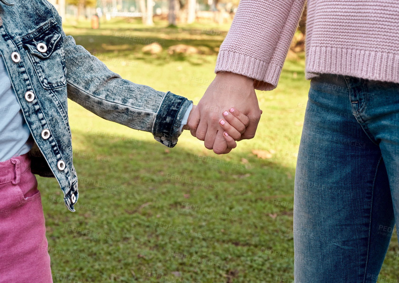 Buy stock photo Cropped shot of a little girl holding her mother’s hand while going for a walk in the park