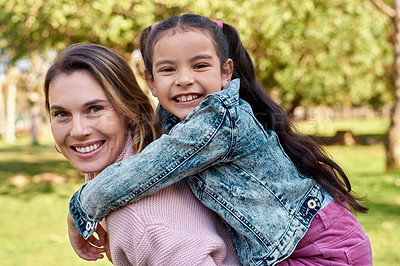 Buy stock photo Shot of an adorable little girl enjoying a piggyback ride with her mother at the park