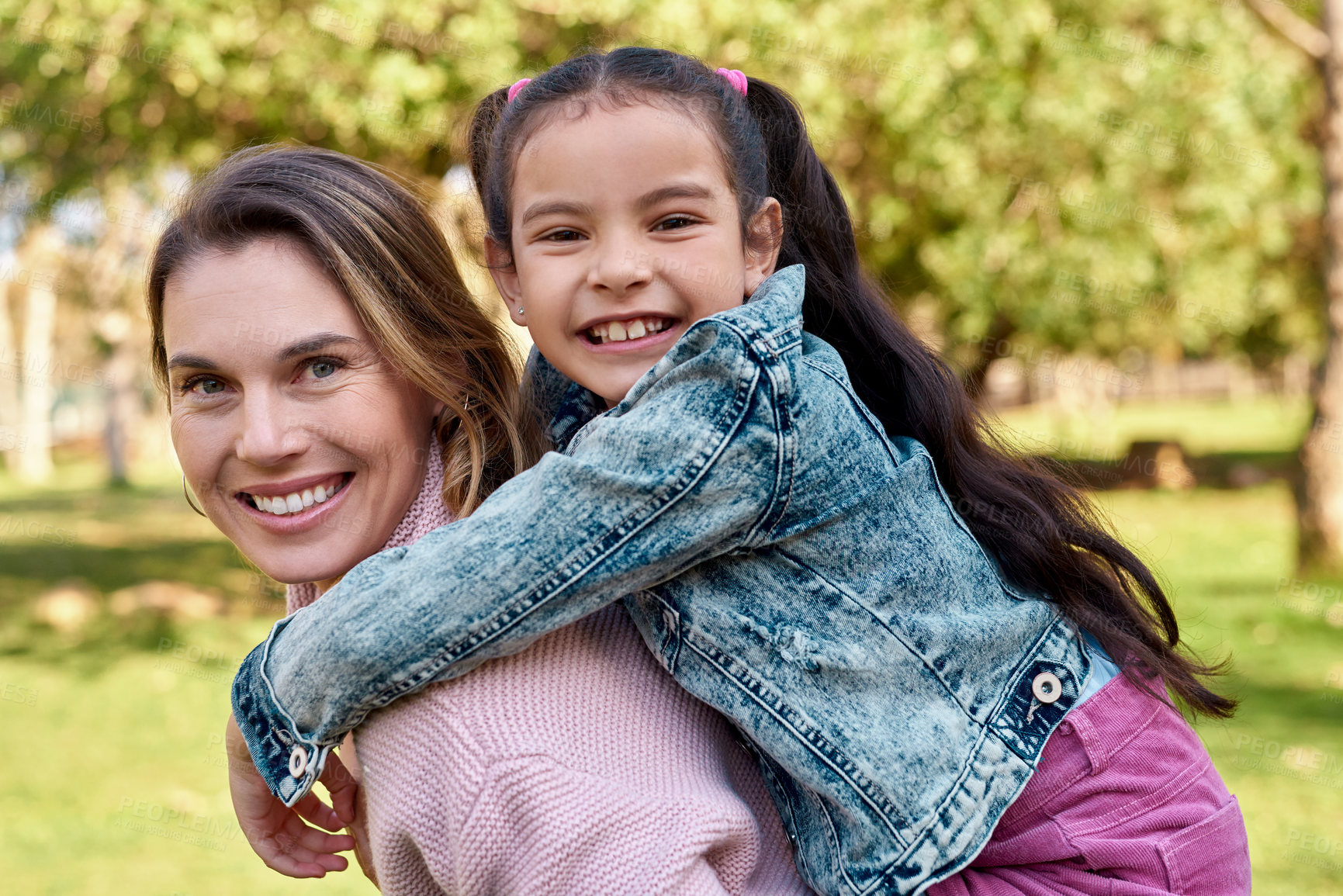 Buy stock photo Shot of an adorable little girl enjoying a piggyback ride with her mother at the park