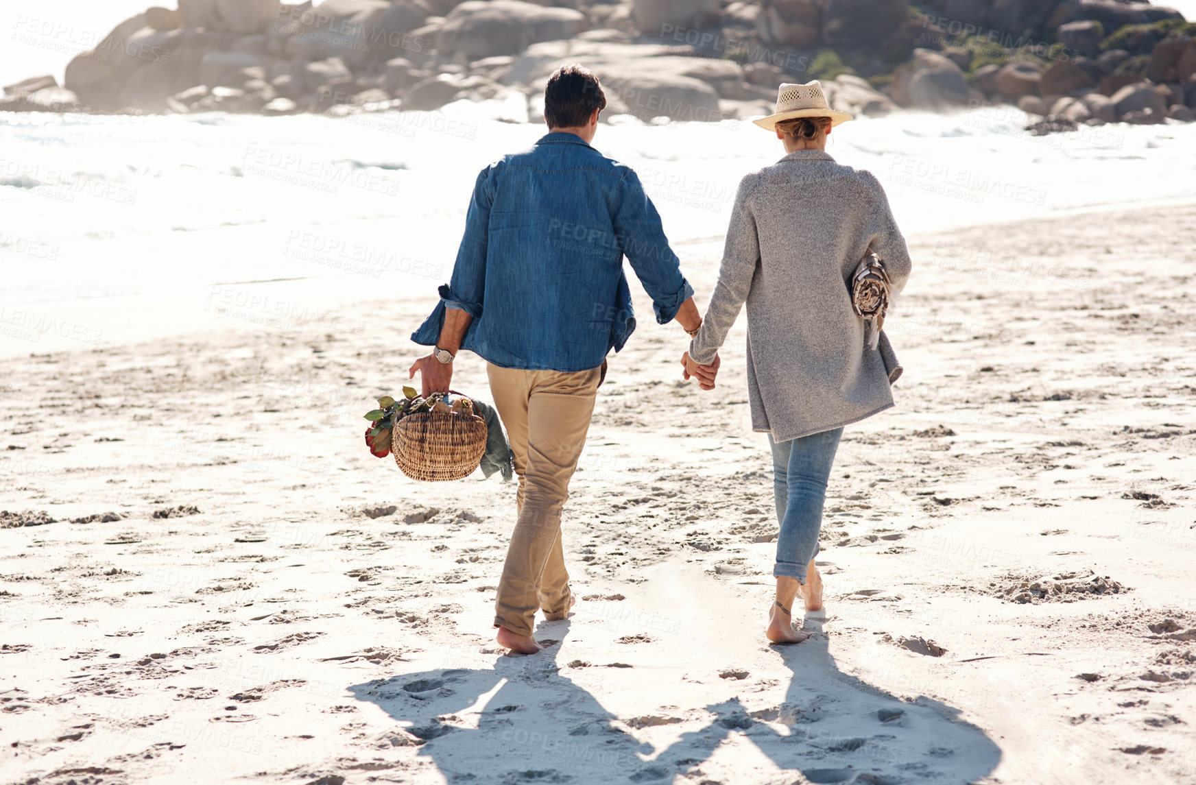 Buy stock photo Couple, walking and holding hands on beach, back and holiday at ocean for vacation and adventure. Summer, travel and romantic picnic date with basket in bali, bonding at sea or outdoor on sand