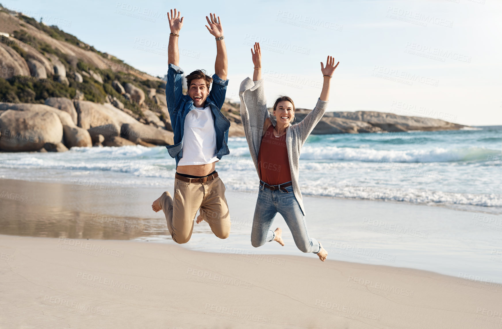Buy stock photo Beach, portrait and couple jump together for vacation, travel and holiday fun or quality time. Happy, man and woman by ocean with love excited for memories, relationship and bonding in California