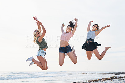 Buy stock photo Shot of three friends jumping into mid air on the beach