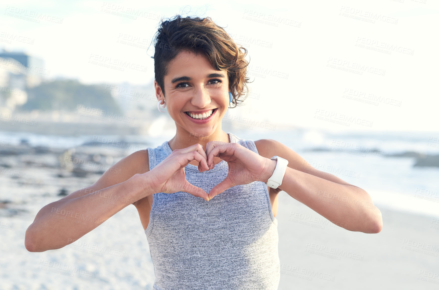 Buy stock photo Cropped shot of a woman forming a heart shape with her hands at the beach