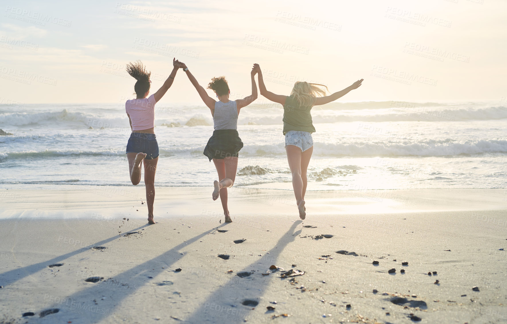 Buy stock photo Back, group and friends on beach for hands up, freedom and bonding together on vacation in California. Sand, waves and celebration of women for travel fun, adventure and jump on holiday in ocean