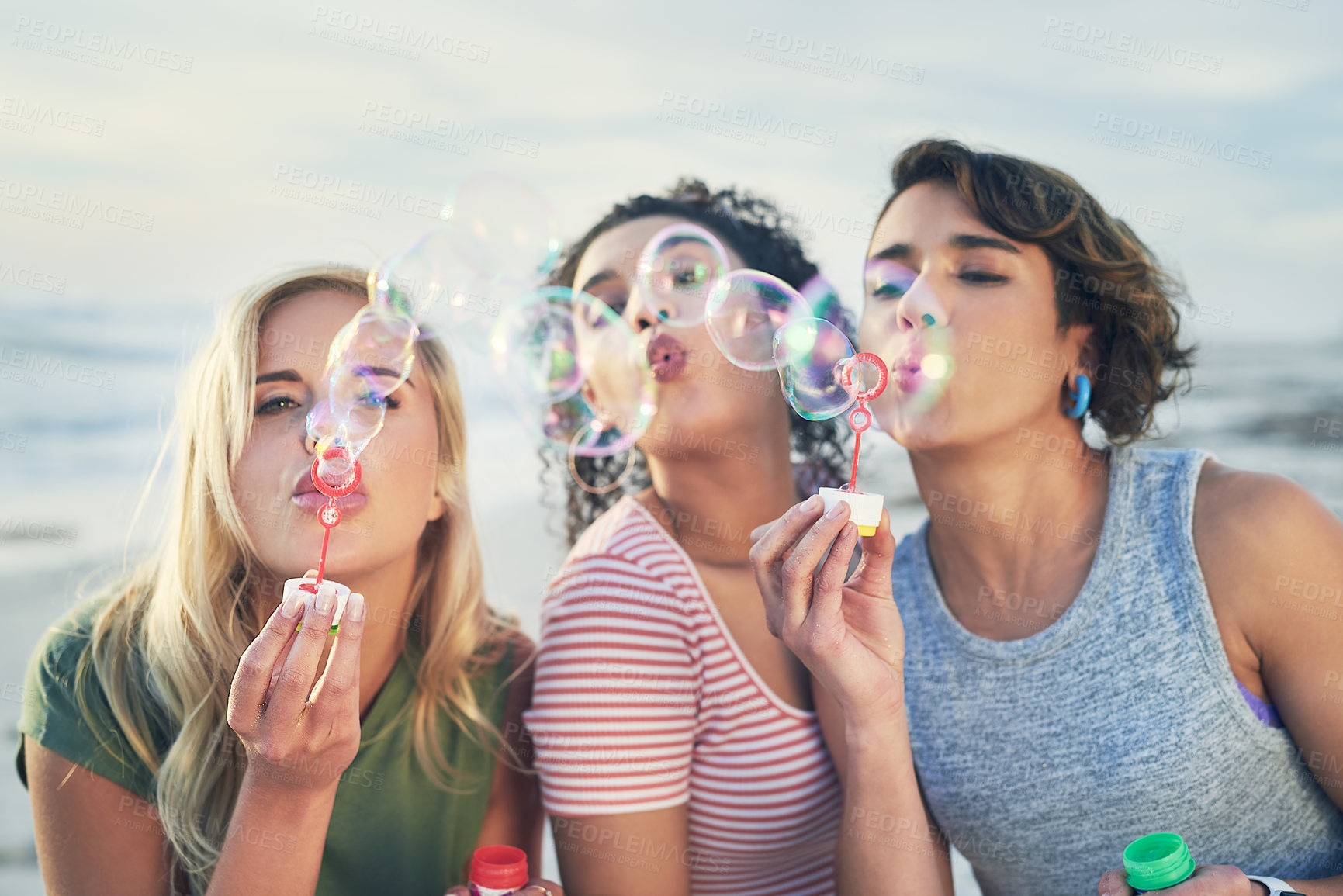 Buy stock photo Cropped shot of three friends blowing bubbles at the beach