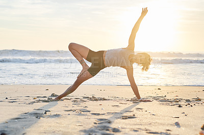 Buy stock photo Shot of a young woman practising yoga on the beach