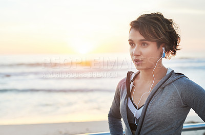 Buy stock photo Cropped shot of a young woman wearing earphones while out for a run